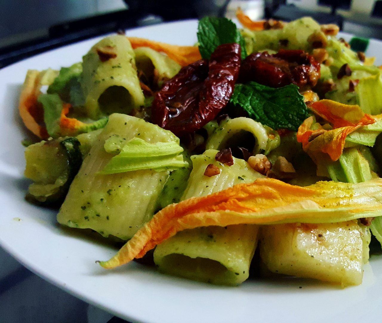 Mezze Maniche mit Zucchinipesto, getrockneten Tomaten, gerösteten Haselnüssen und Zucchiniblüten