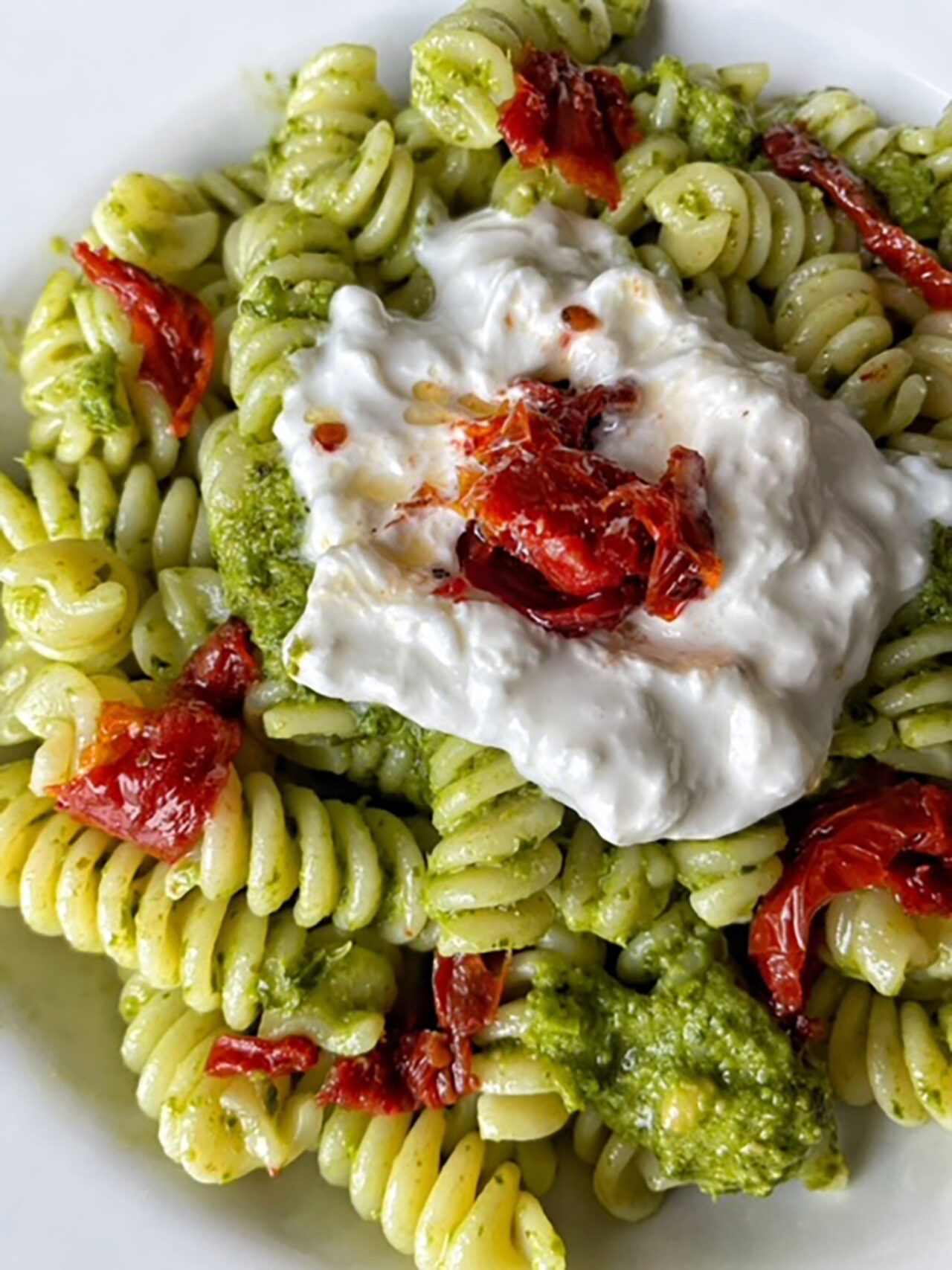 Fusilli cremosi al pesto di basilico, stracciatella e pomodori secchi