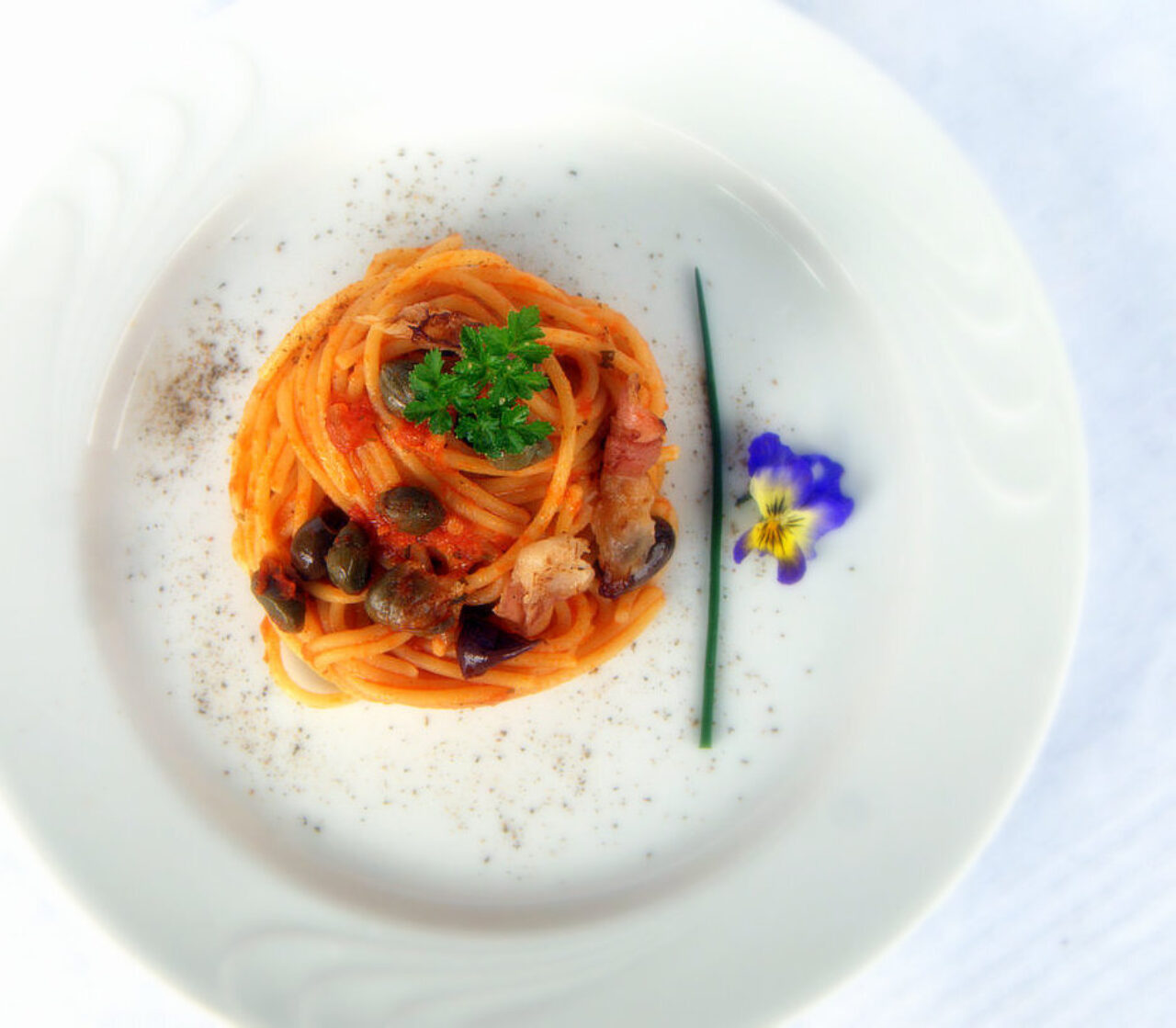 Spaghetti mit Tomatensauce mit knusprigem Speck, Taggiasca-Oliven und Kapern