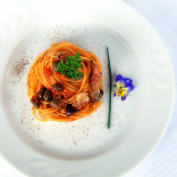 Spaghetti mit Tomatensauce mit knusprigem Speck, Taggiasca-Oliven und Kapern